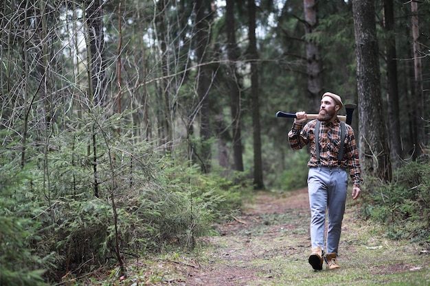 大きな斧を持ったあごひげを生やした木こりは、伐採前に木を調べますxA