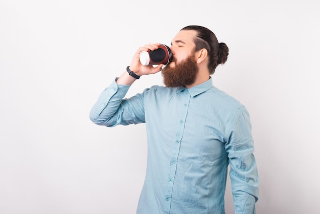 Bearded male business man is enjoying his take away coffee.