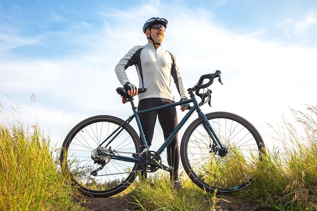 Bearded male cyclist is resting with a bike on the road in nature cycling and health hobbies