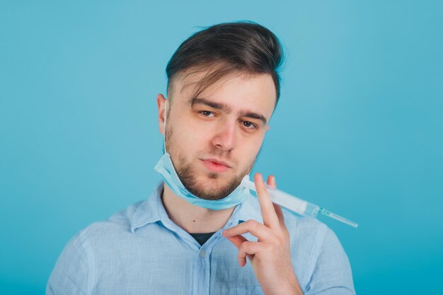 bearded male doctor and holding syringe and shouting on blue background