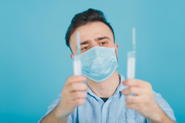 bearded male doctor and holding syringe and shouting on blue background