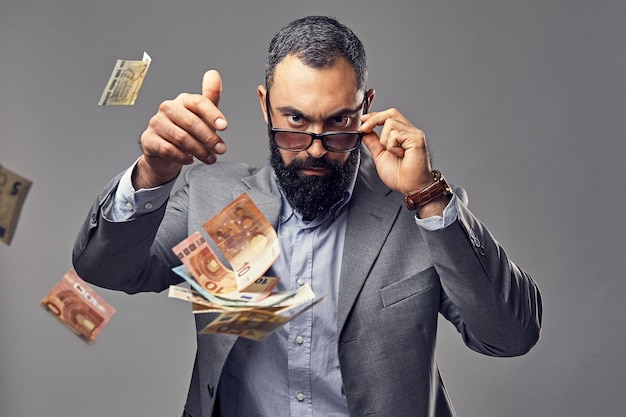 Bearded male dressed in a suit catch money banknote in the air.