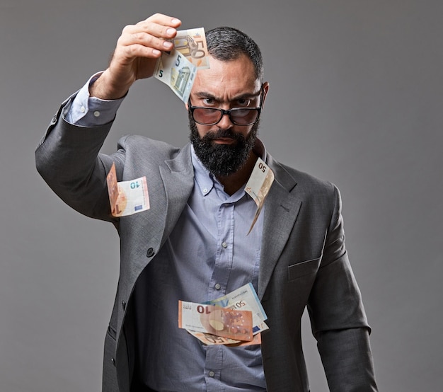 Bearded male dressed in a suit catch money banknote in the air.