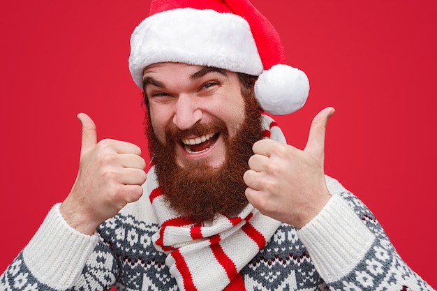 bearded male in Santa hat showing thumb up gesture