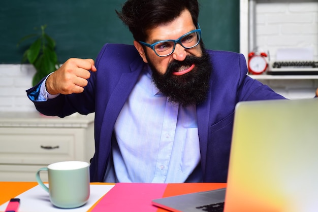 Bearded male student in glasses student preparing for test or exam angry male university student