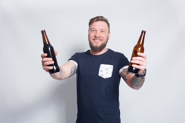 Photo bearded male with tattooed arm holding beer bottles