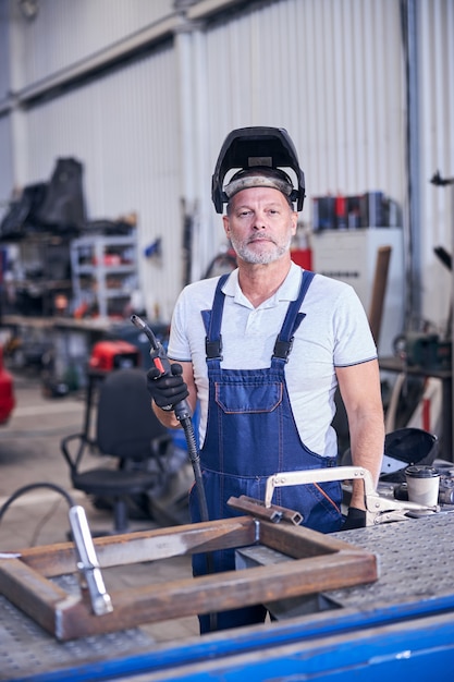 Bearded male worker using welding torch in garage