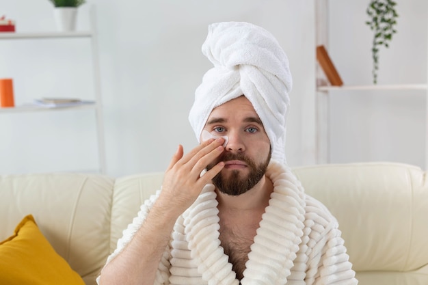 Bearded man applying eye patches on his face wrinkles and face home care for men