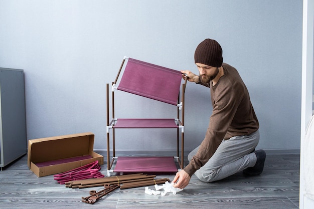 Bearded man assembles a shelf for the rack