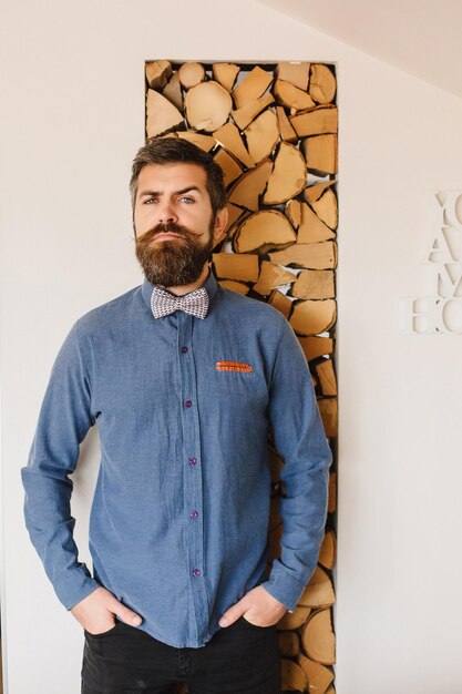 Bearded man on the background of the wall with a cut tree for\
the fireplace