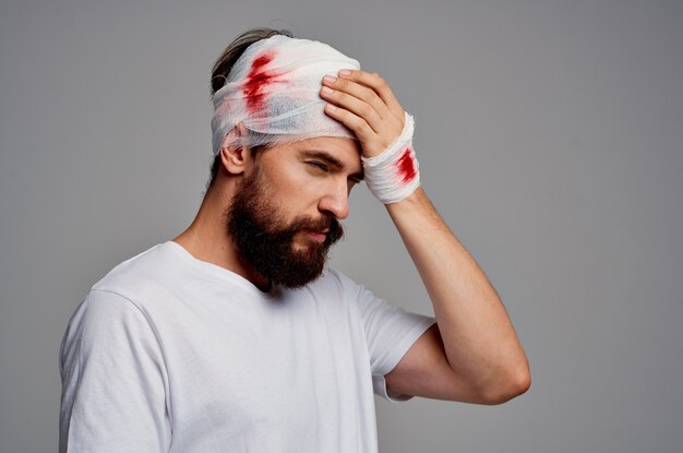 Bearded man bandaged head and hand blood light background. high\
quality photo
