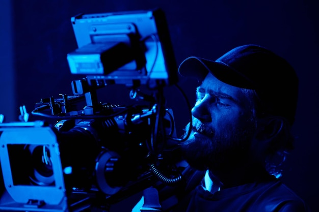 Bearded man in baseball cap looking on small screen on video camera