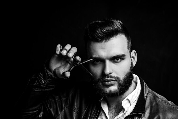 Bearded man bearded male portrait of stylish man with beard barber scissors and straight razor barbe