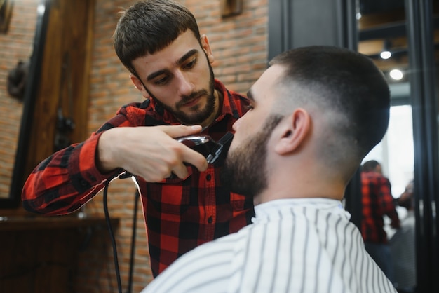 Foto uomo barbuto, maschio barbuto. barbiere vintage, rasatura. ritratto di barba uomo alla moda. forbici da barbiere e rasoio, negozio di barbiere. stile della barba. concetto di negozio di barbiere pubblicitario. bianco e nero