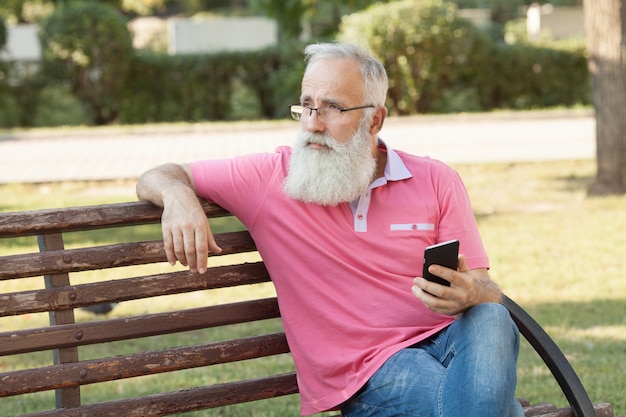 Bearded man on a bench using a phone