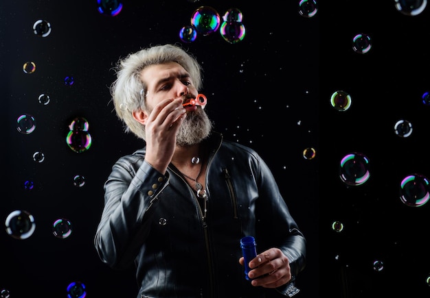 Bearded man blowing soap bubbles good mood childhood and happiness concept play with bubble