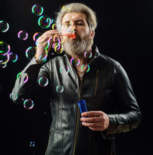 Bearded man blowing soap bubbles. Happiness. Good mood. Childhood.