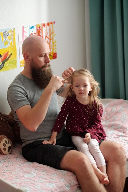 Foto uomo barbuto che intreccia i capelli di sua figlia.