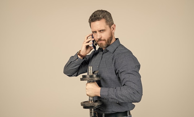 Bearded man businessman training with barbell and speaking on smartphone agile business