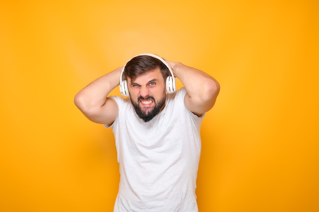 Bearded man clutched his head in despair and listens to music on headphones.