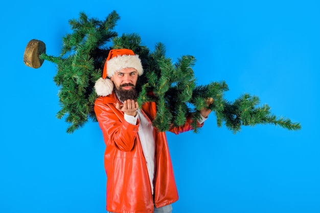 Bearded man in costume of santa claus holds christmas tree sends air kiss christmas santa man