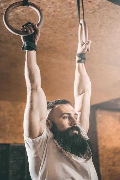 Bearded man crossfit training. rings.