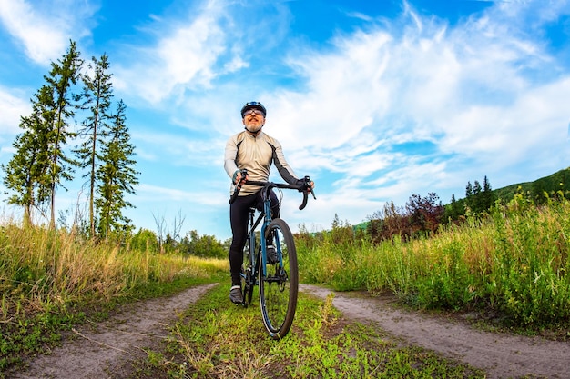 bearded man cyclist rides a bike on a road in nature sports hobbies and entertainment for health