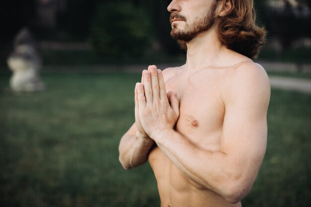 Bearded man doing yoga in the green park 