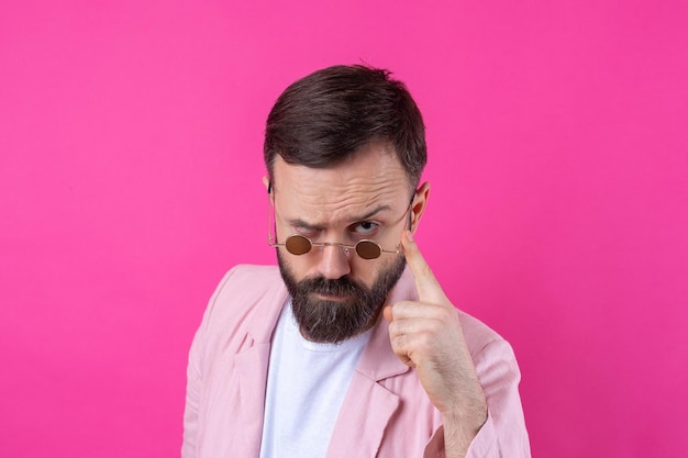 Bearded man dressed in a pink jacket with glasses emotional studio portrait