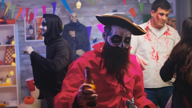 Bearded man dressed up like a pirate celebrating halloween with a group of friends disguised like different monsters