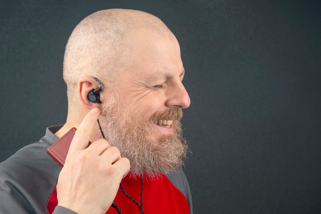 Bearded man enjoys listening to his favorite music through an audio player in small headphones. audiophile and music lover. music and hi-fi sound.