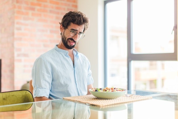 Bearded man feeling disgusted and irritated, sticking tongue out, disliking something nasty and yucky