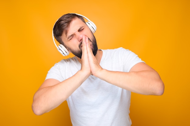 Bearded man folded his palms in front of his face and listens to emotional music