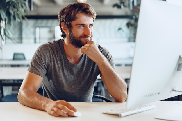 Bearded man freelancer using computer in a modern coworking place