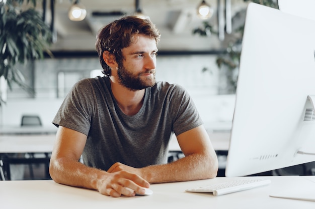 Bearded man freelancer using computer in a modern coworking place