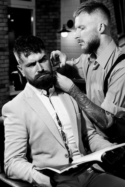Bearded man getting haircut by hairdresser at barbershop