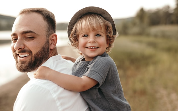 Photo bearded man giving piggyback ride to cute blond boy