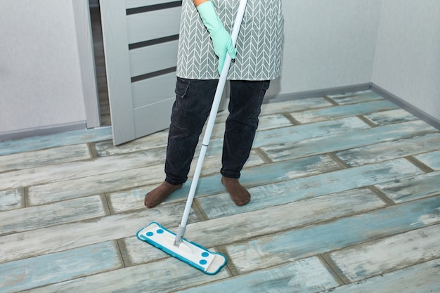 Bearded man in gloves with mop in hand