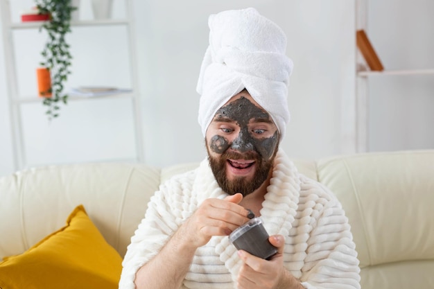 Bearded man has clean fresh skin wears beauty clay mask on face and enjoys beauty treatments spa at