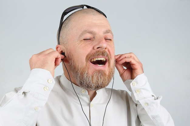 Бородатый мужчина в наушниках слушает музыку