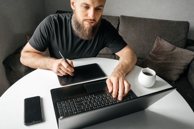 Photo bearded man on his workplace at laptop