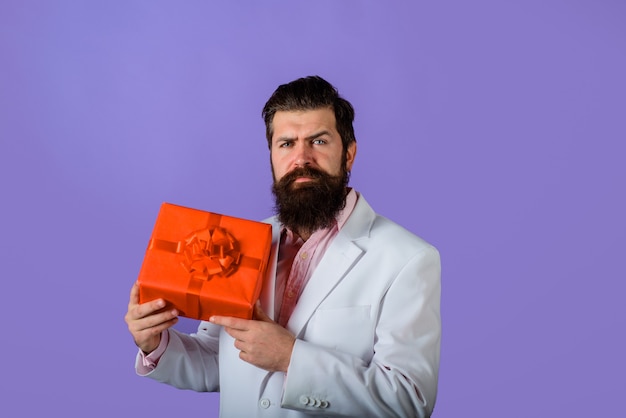 Фото Бородатый мужчина держит подарочную коробку привлекательный мужчина с подарком бизнесмен держит подарочную коробку день святого валентина