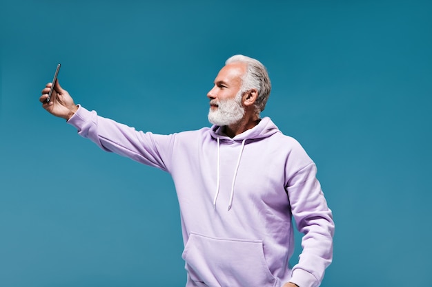 Bearded man in hoodie takes selfie