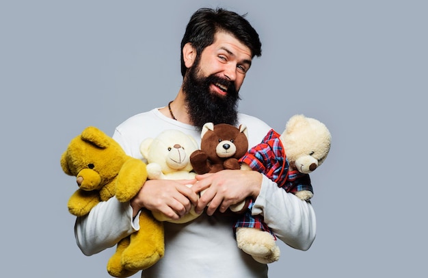 Бородатый мужчина обнимает много плюшевых мишек счастливый парень с плюшевыми игрушками плюшевый мишка подарок на день рождения