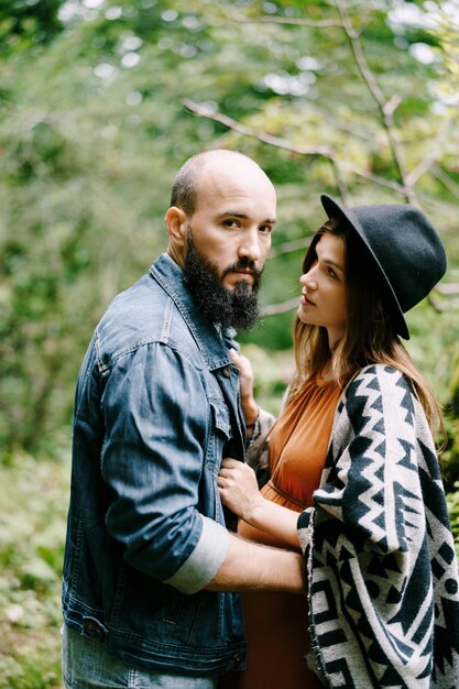 Bearded man hugs a pregnant woman in the park portrait