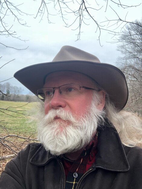 Foto bearded man in hoed die wegkijkt terwijl hij buiten staat