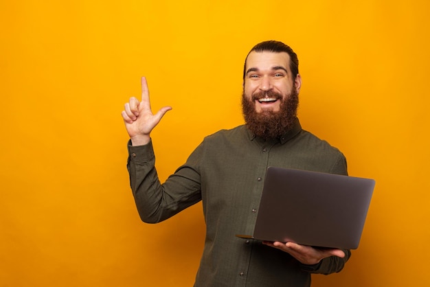Бородатый мужчина указывает на место для копирования, держа ноутбук