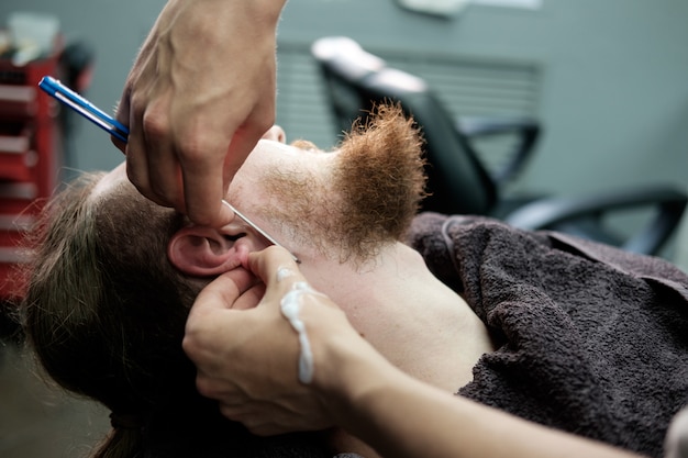 Bearded man is shaved at the barbershop