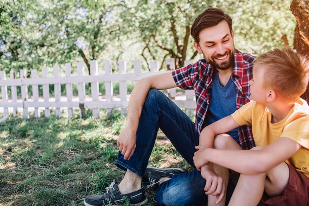 Bearded man is sitting and looking at small boy