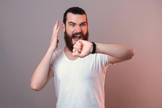 Bearded man is stressed because of the time while watching his watch